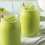 Deux verres de smoothie à l'avocat sur une table en bois.